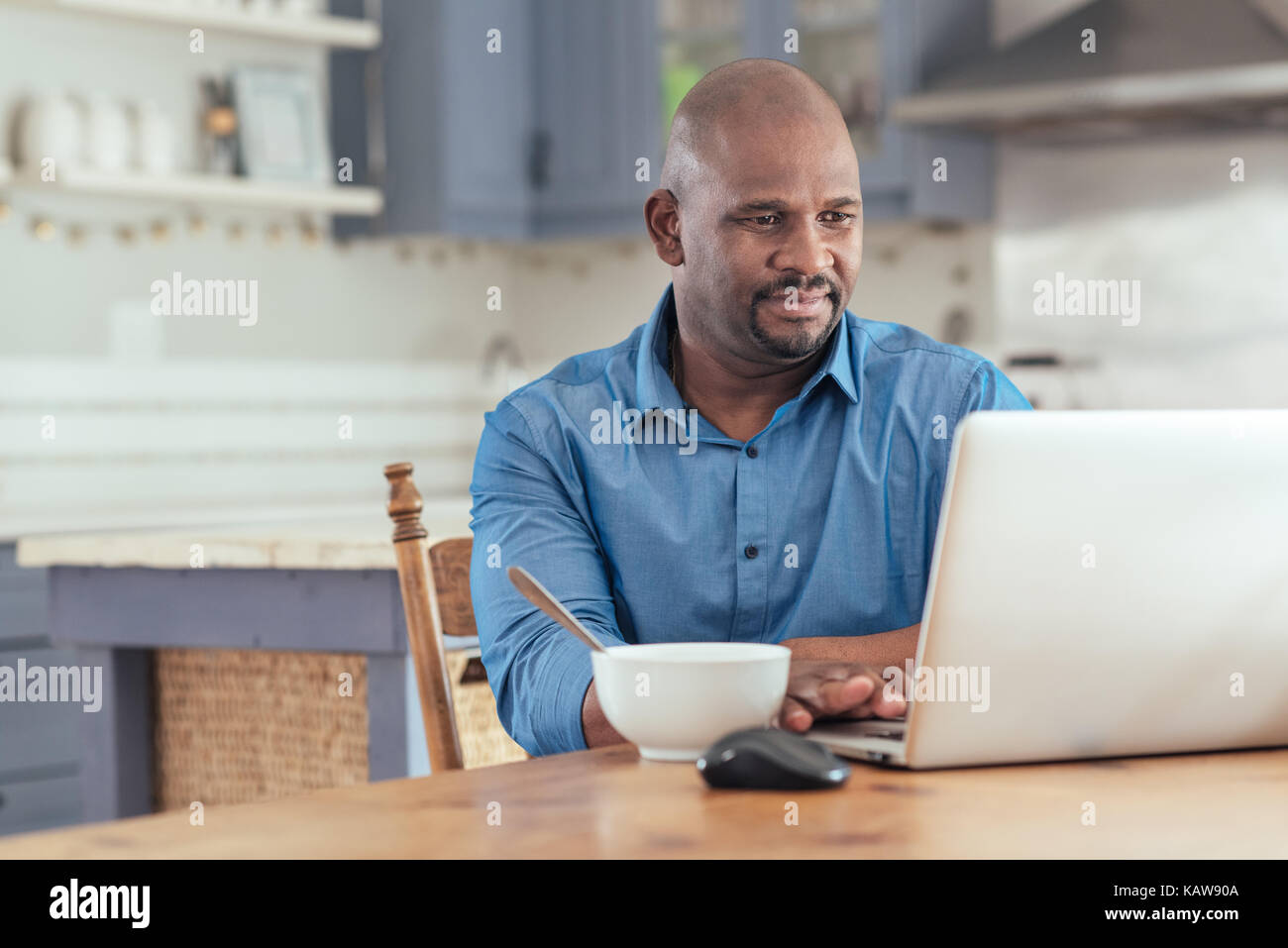 Mature African man using a laptop over breakfast Stock Photo