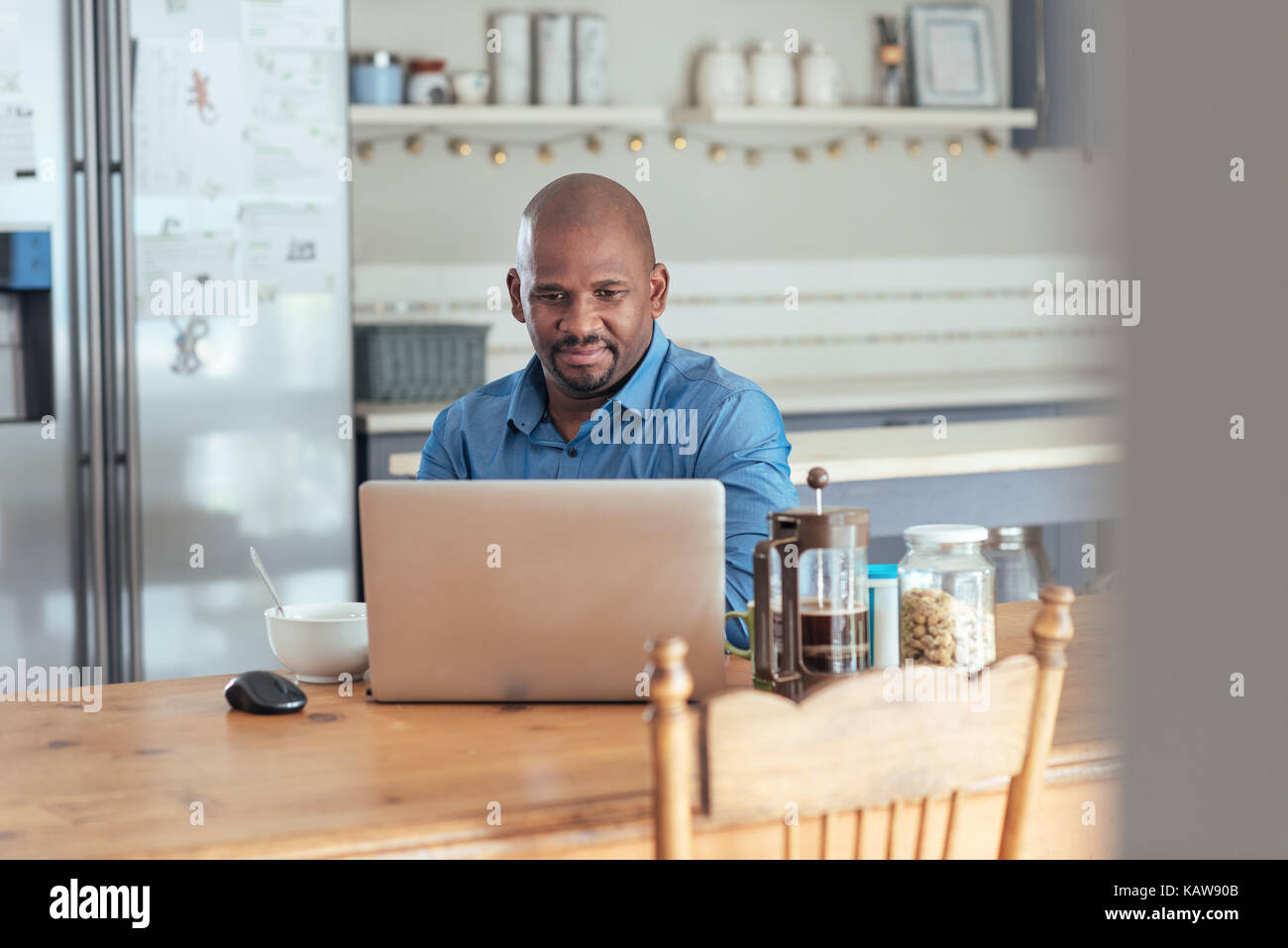 Smiling mature African man using a laptop over breakfast Stock Photo