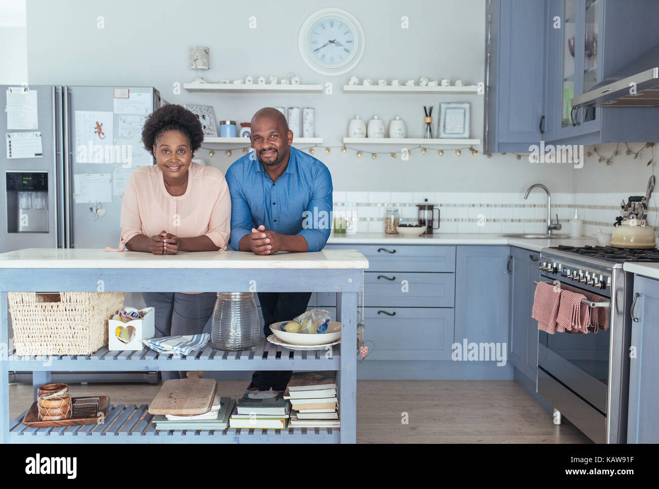 Smiling African couple leaning on their kitchen island at home Stock Photo