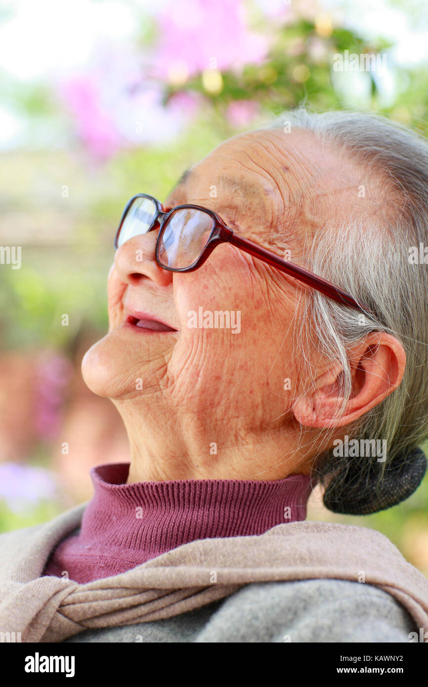 One happy Senior Chinese woman reading book in the yard Stock Photo