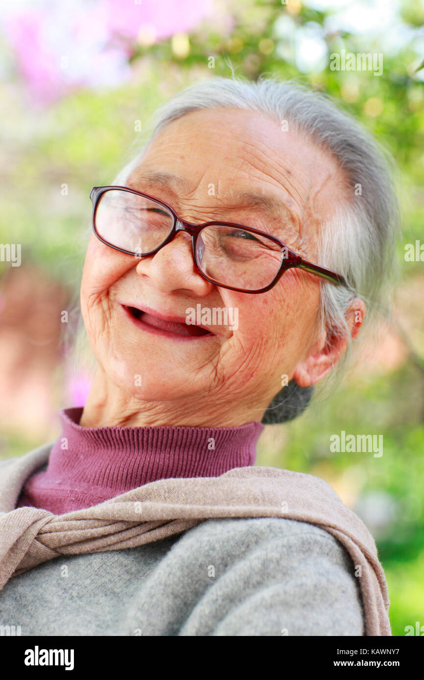 One happy Senior Chinese woman reading book in the yard Stock Photo