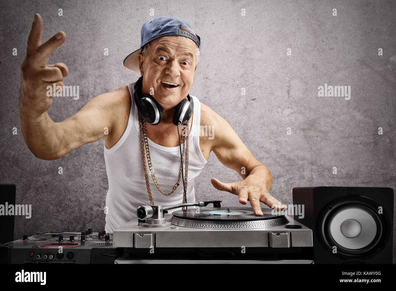 Elderly DJ making a peace sign against a rusty gray wall Stock Photo
