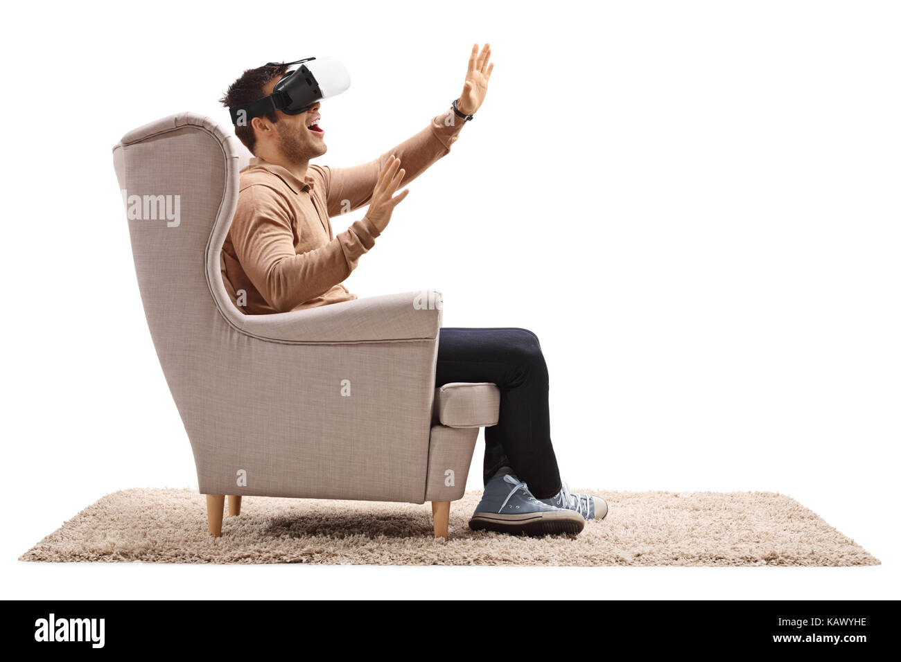 Young man seated in an armchair using a virtual reality headset ...