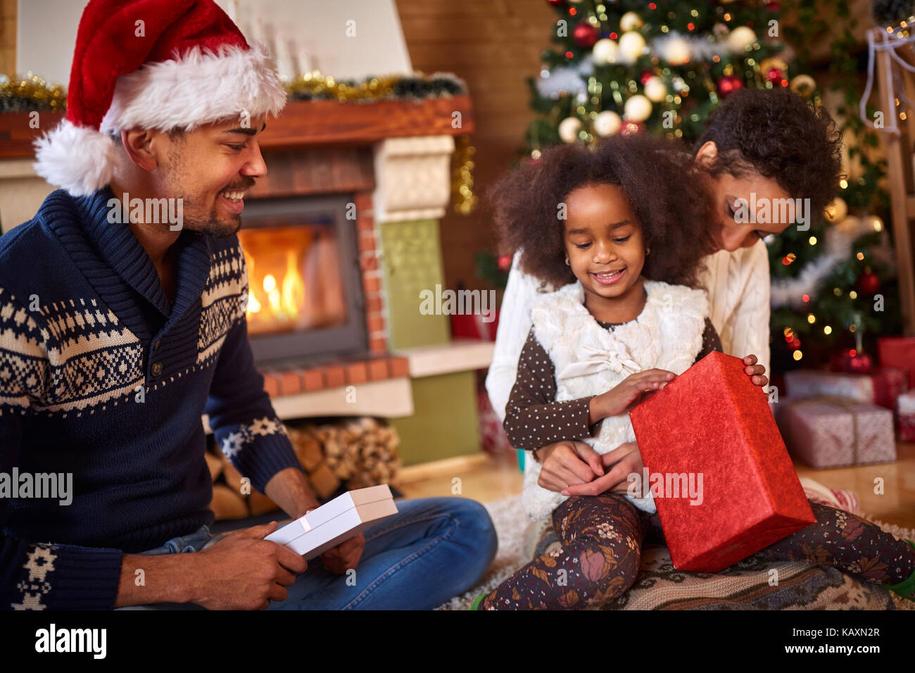 Afro American family with happy little girl opening Christmas present Stock Photo