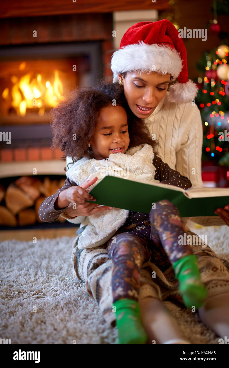 Young afro American mom with daughter reading Christmas fairytales Stock Photo