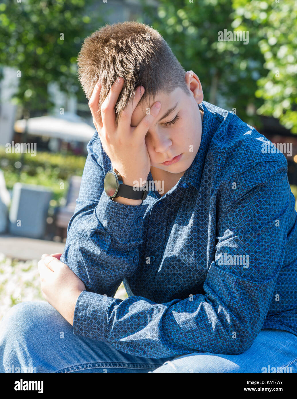 Sad teenager sitting on street Stock Photo