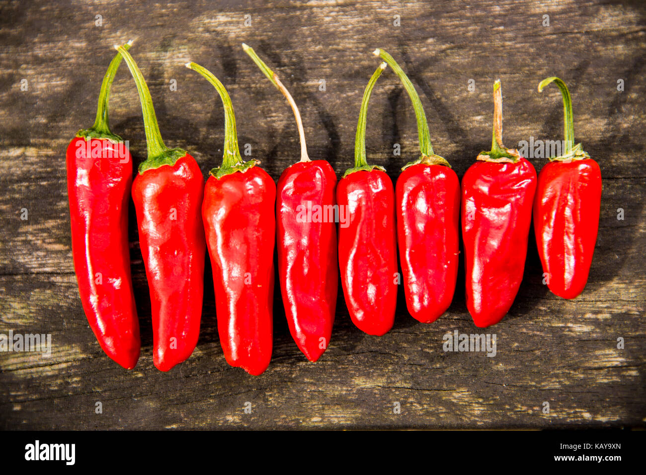 Red Chilli Peppers on a Wooden Background Stock Photo - Alamy
