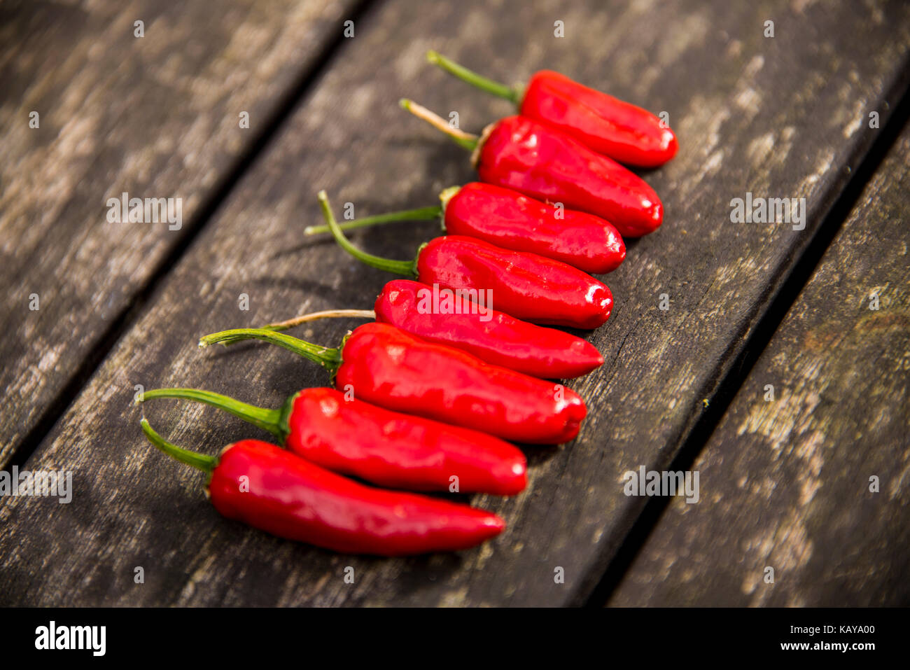 Red Chilli Peppers on a Wooden Background Stock Photo - Alamy