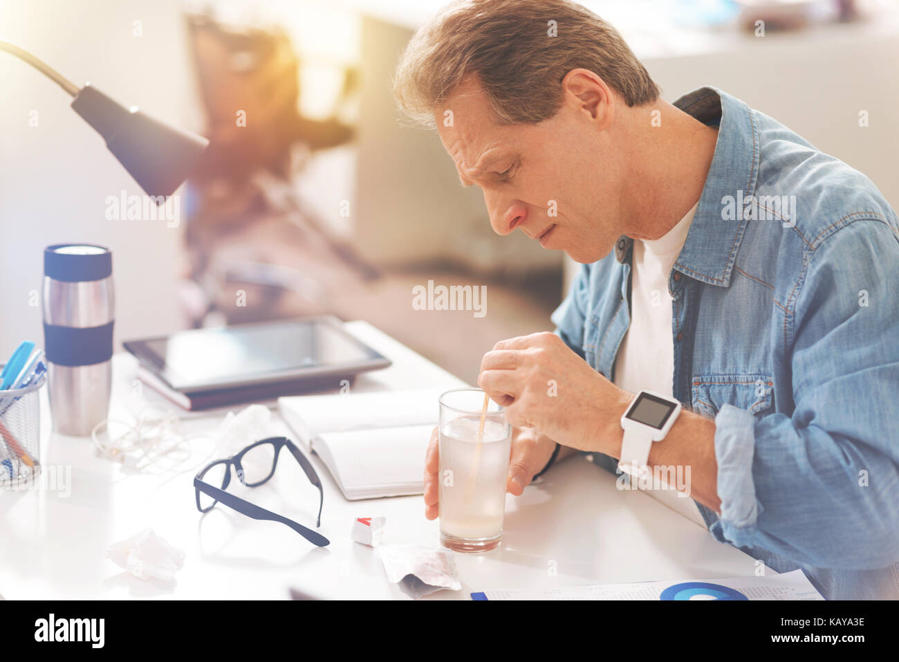 Cheerless mature man dissolving medicines in hot water Stock Photo