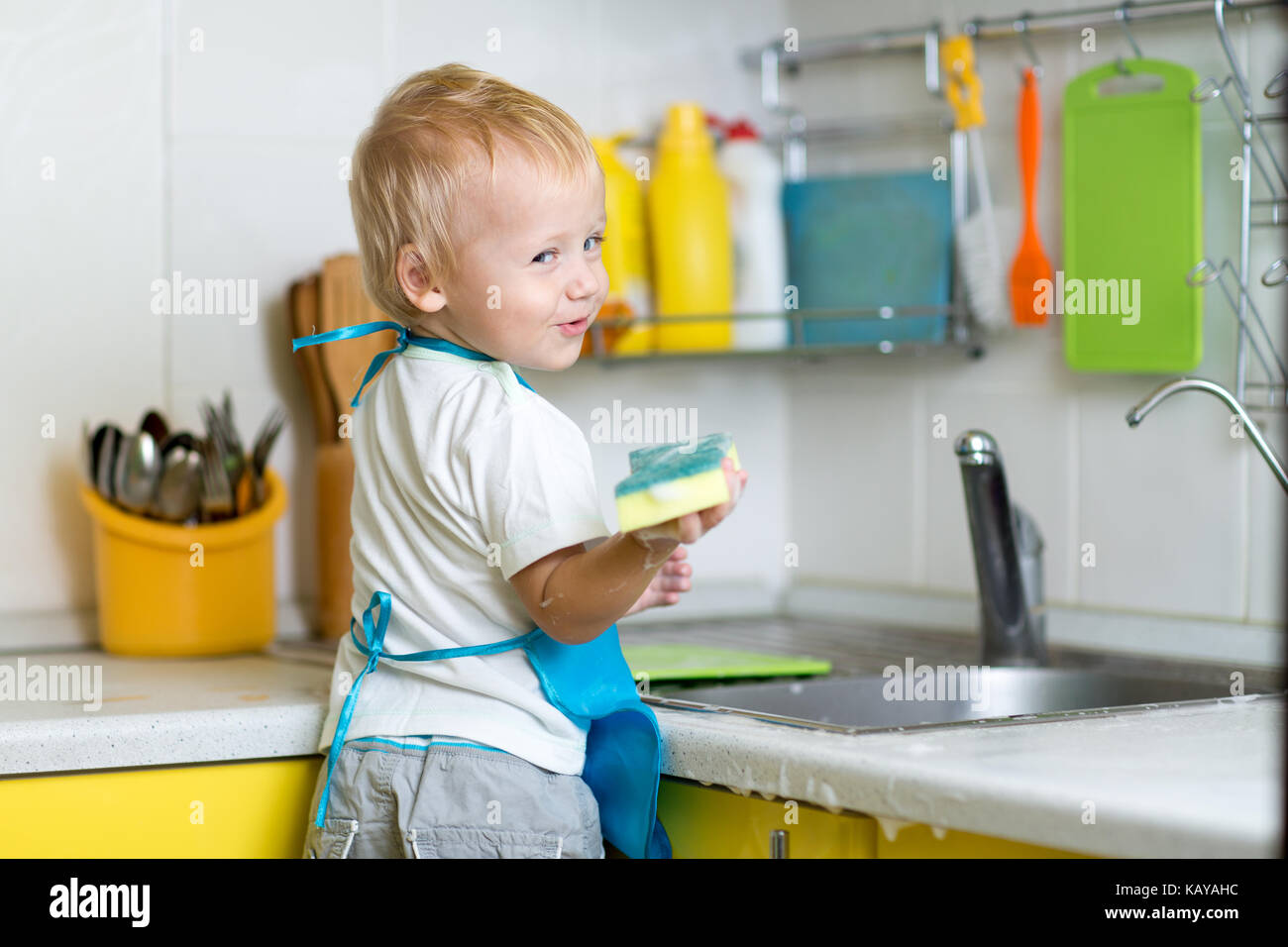 Little boy helping mother washing dishes in the kitchen Stock Photo