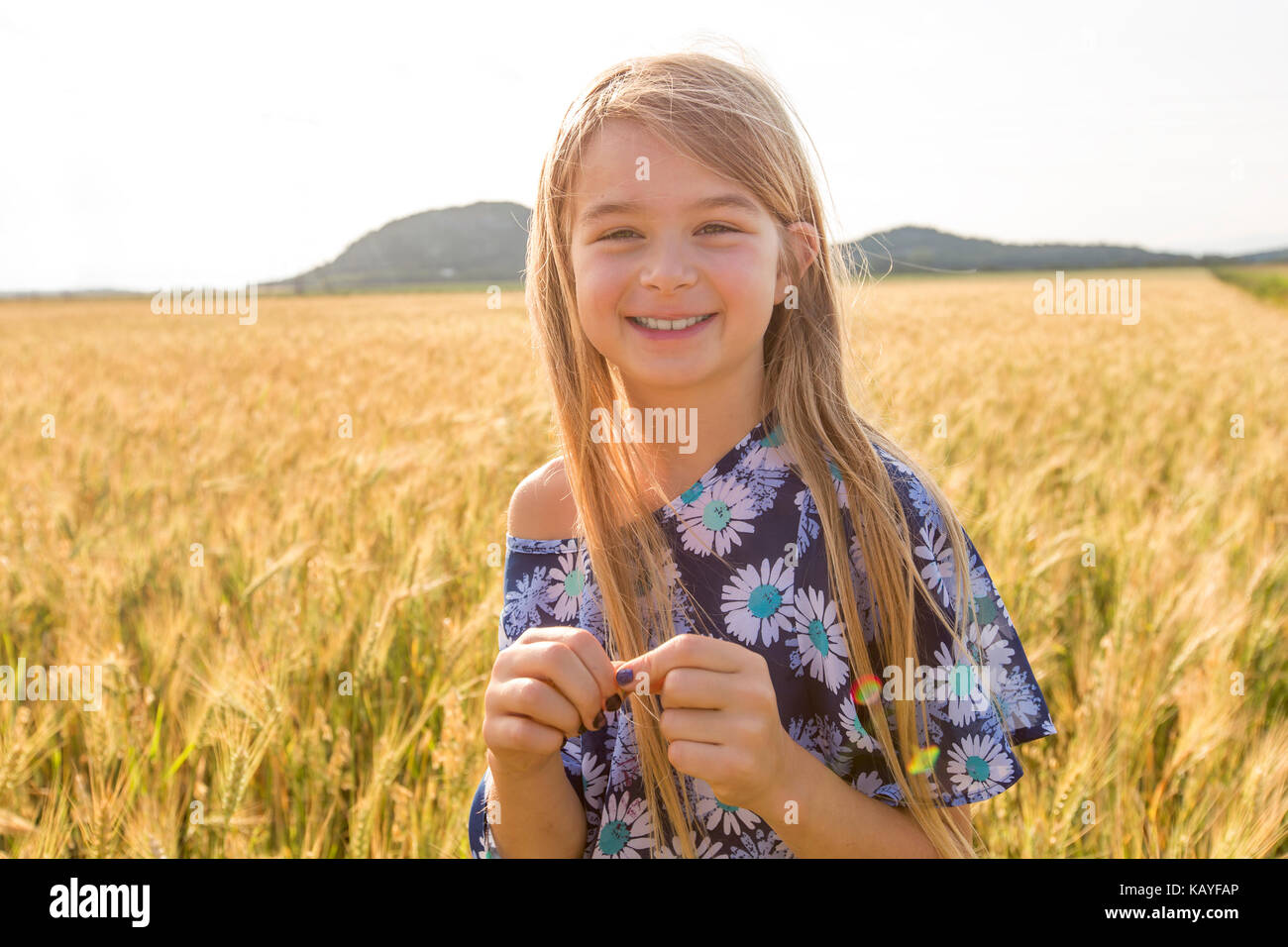 Adorable little girl playing in the wheat field on a warm summer day ...