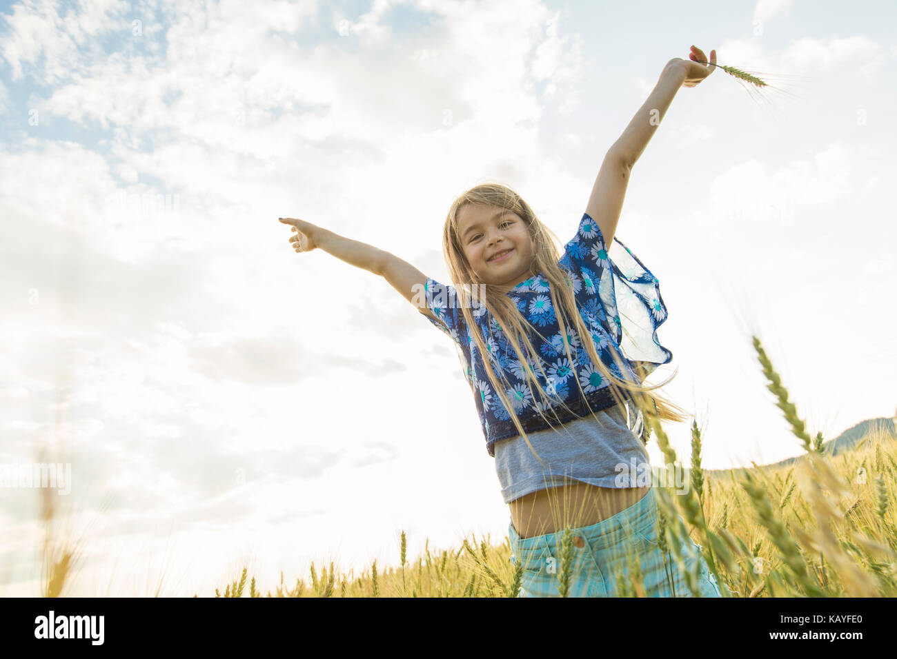 Adorable little girl playing in the wheat field on a warm summer day ...