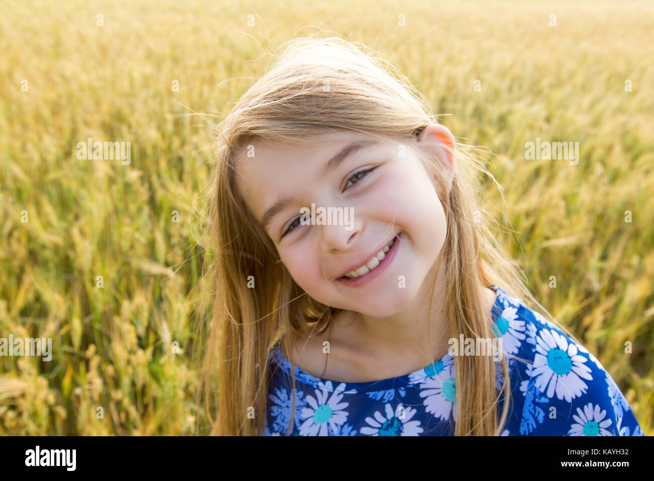Adorable little girl playing in the wheat field on a warm summer day ...