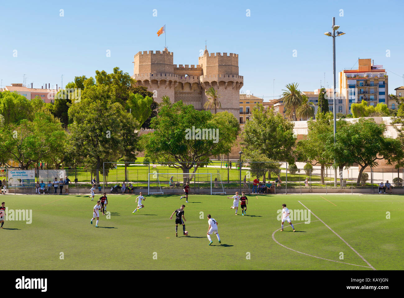 Valencia Rio Turia garden, overlooked by the Torres Serranos city gate, teenagers play a football match on a pitch in the Turia riverbed garden, Spain Stock Photo
