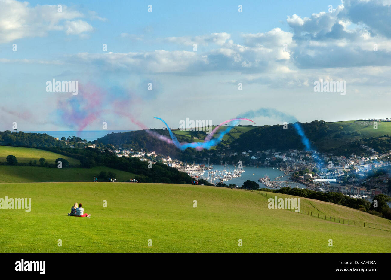 Two woman sitting in an elevated field in Kingswear watching the Red Arrows aerobatic team give a display at the Dartmouth Regatta. Stock Photo