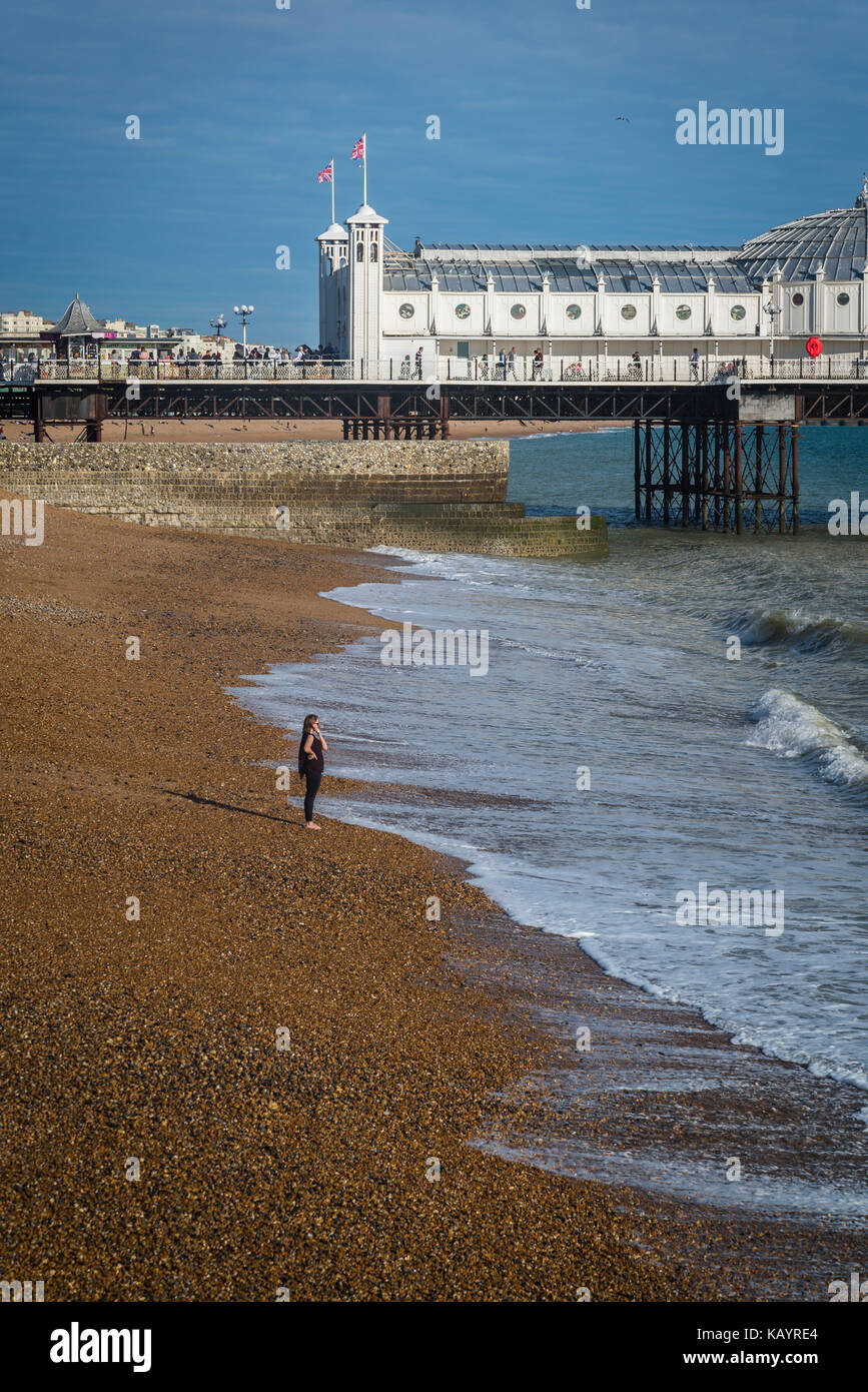 Woman standing on the beach and Brighton Palace Pier, Brighton, England, UK Stock Photo