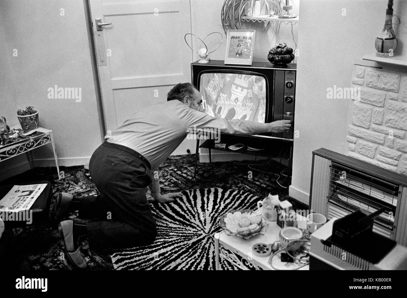 Family at home London 1970s in living room interior tuning in TV  changing channel to watch watching The Regiment staring John Hallam  and Wendy Williams 1972 UK HOMER SYKES Stock Photo