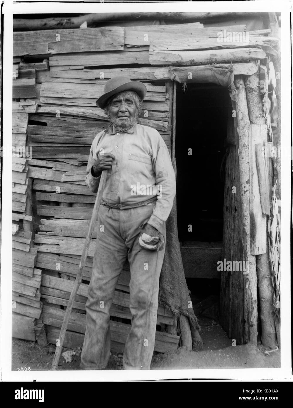 Yokut Indian man standing beside a shake house, Tule River Reservation
