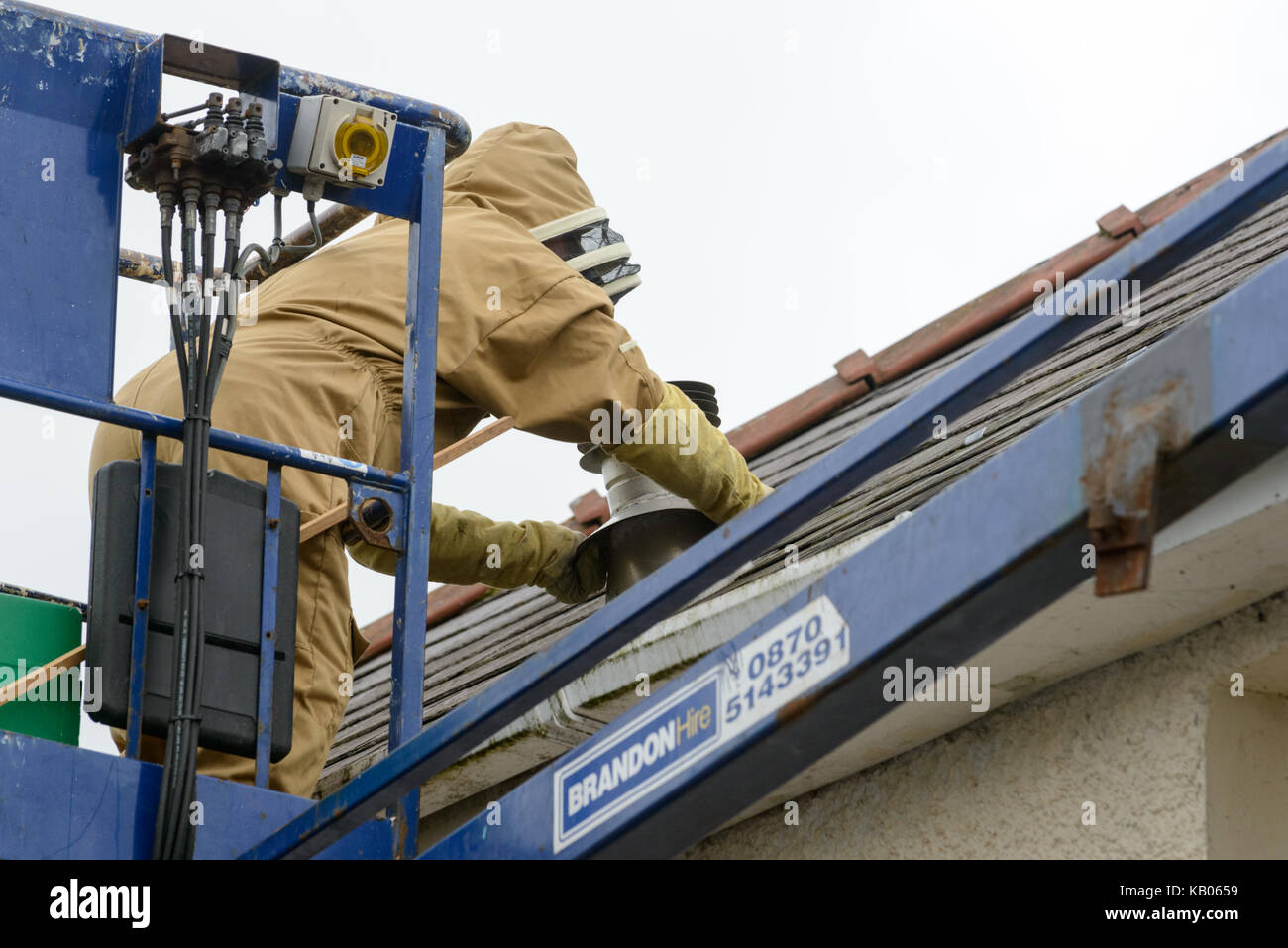 Pest Control specialist installing a brood box in order to encourage a colony of honey bees to move from a house chimney. Stock Photo