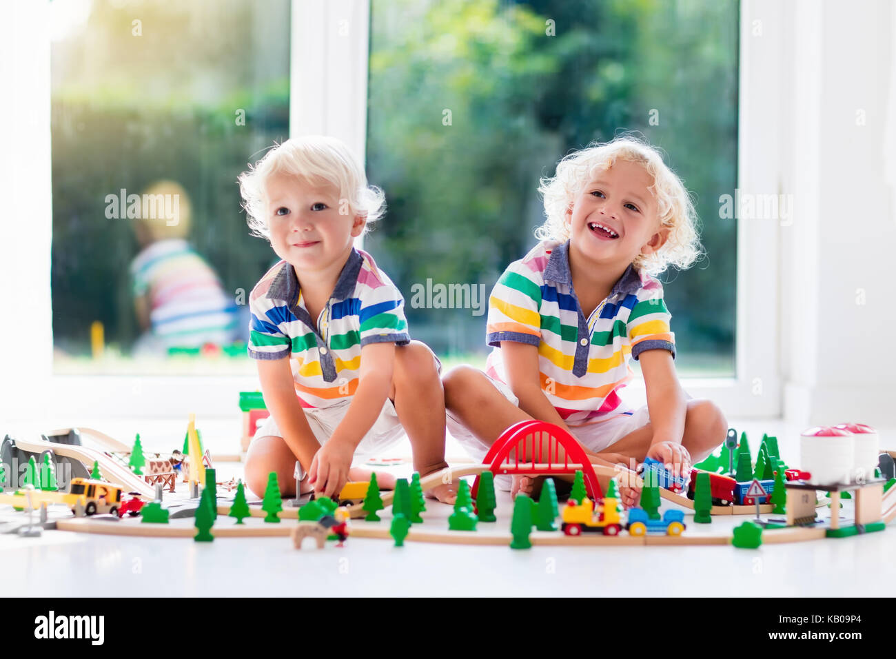 Kids play with toy train railway. Children playing with wooden trains