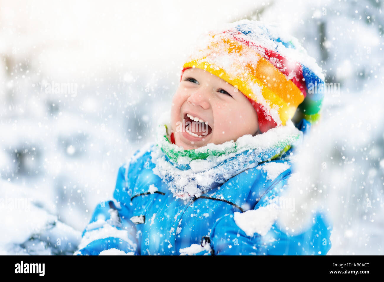 Baby playing with snow in winter. Little toddler boy in blue jacket and ...