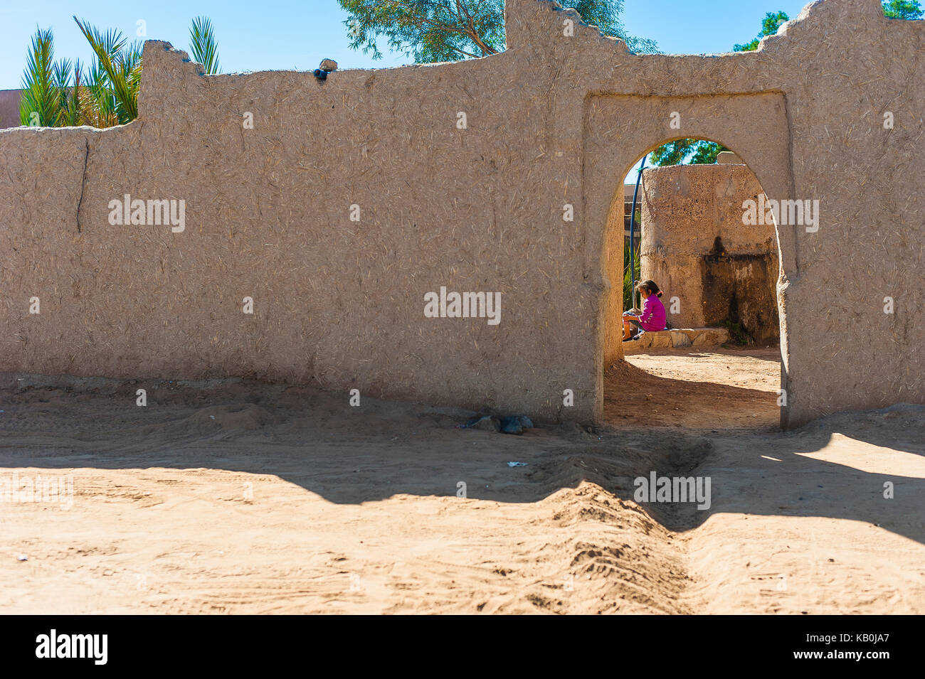 Girl sitting at the  front of her house in Merzouga, Morocco Stock Photo