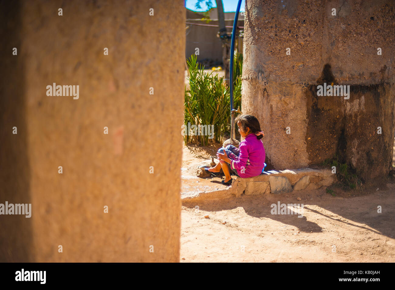 Girl sitting at the  front of her house in Merzouga, Morocco Stock Photo