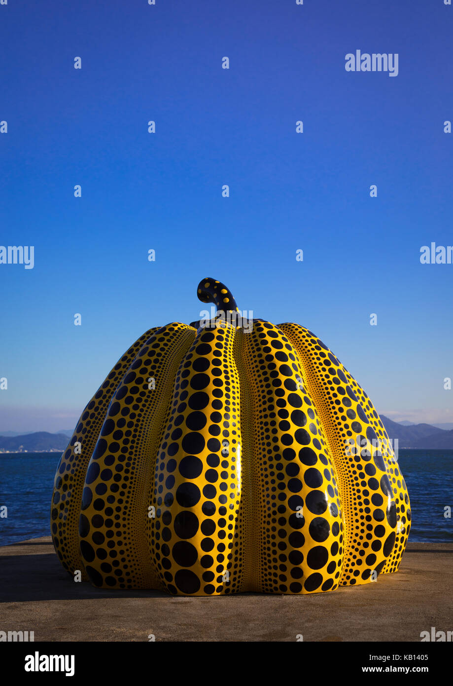 Yellow pumpkin by yayoi kusama on pier at sea, Seto Inland Sea, Naoshima, Japan.  The yellow and famous pumpkin is showcased on the pier facing the Benesse Hotel, the most expensive accommodation on Naoshima island Stock Photo