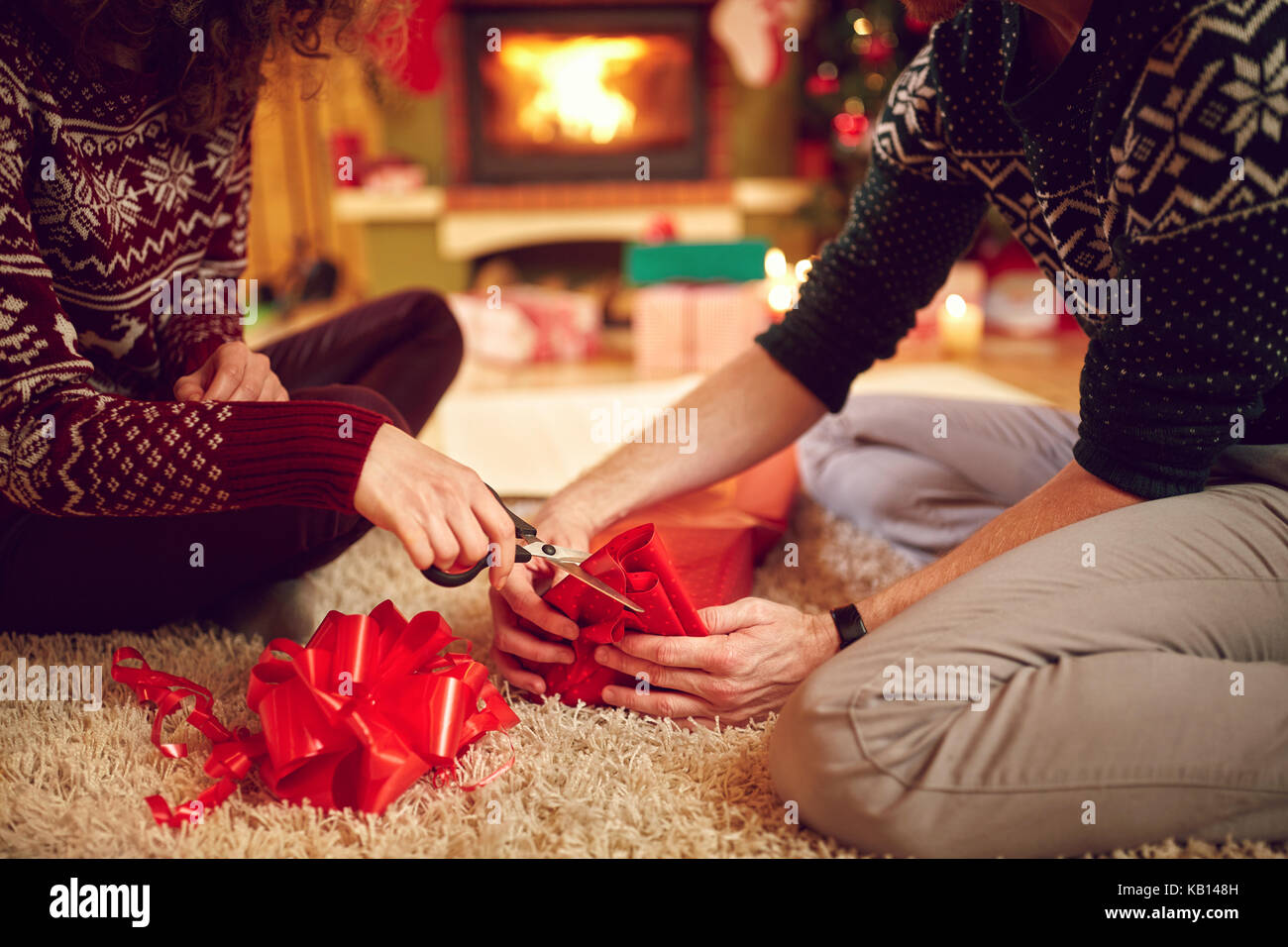 Close up of couple’s hands packing Christmas gifts, concept Stock Photo
