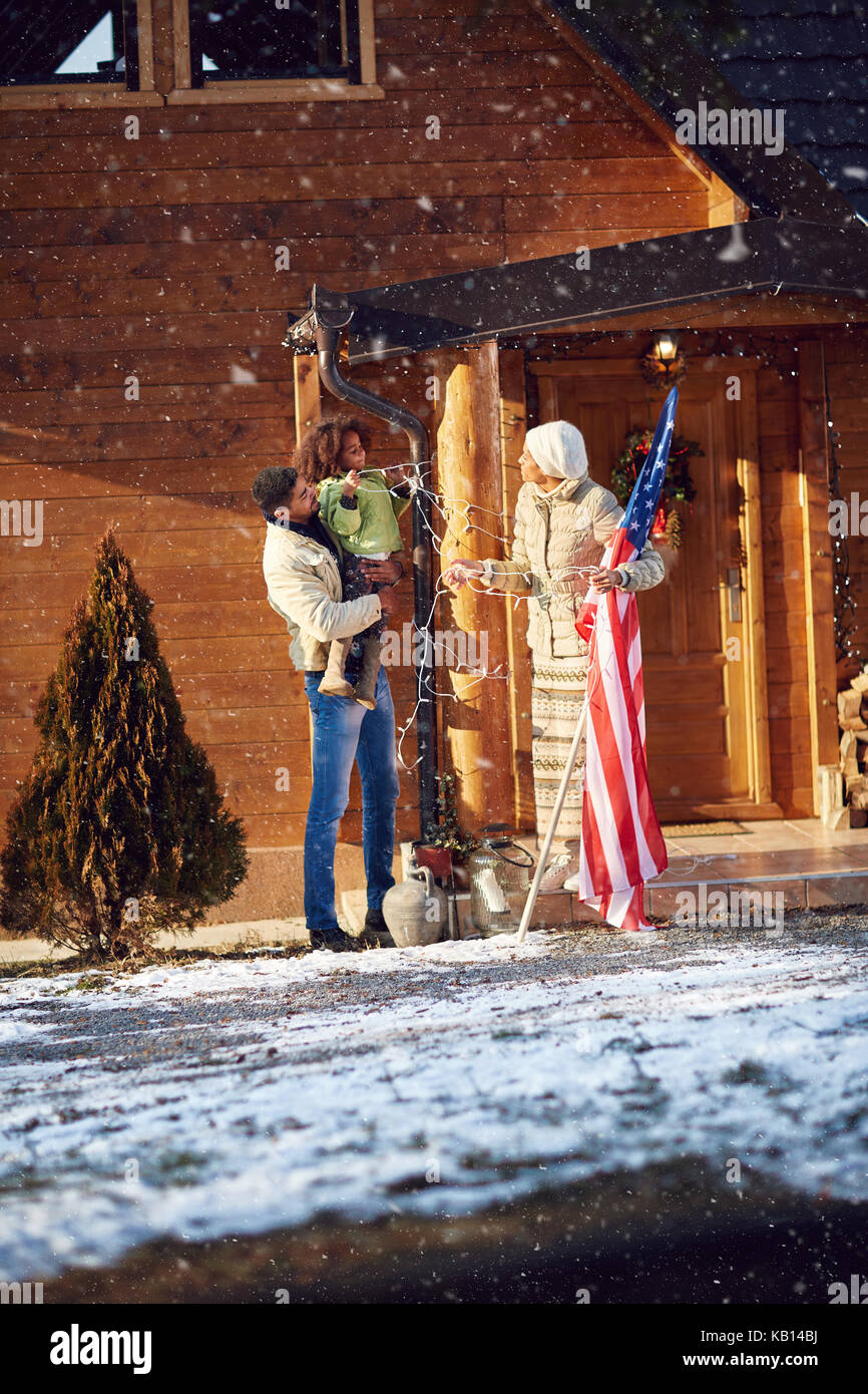 Afro American parents and child decorate house together outdoor for Christmas Stock Photo