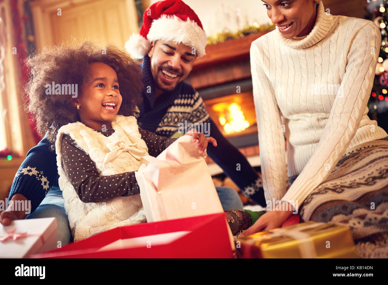 Happy Afro-American family opening Christmas presents at home Stock Photo
