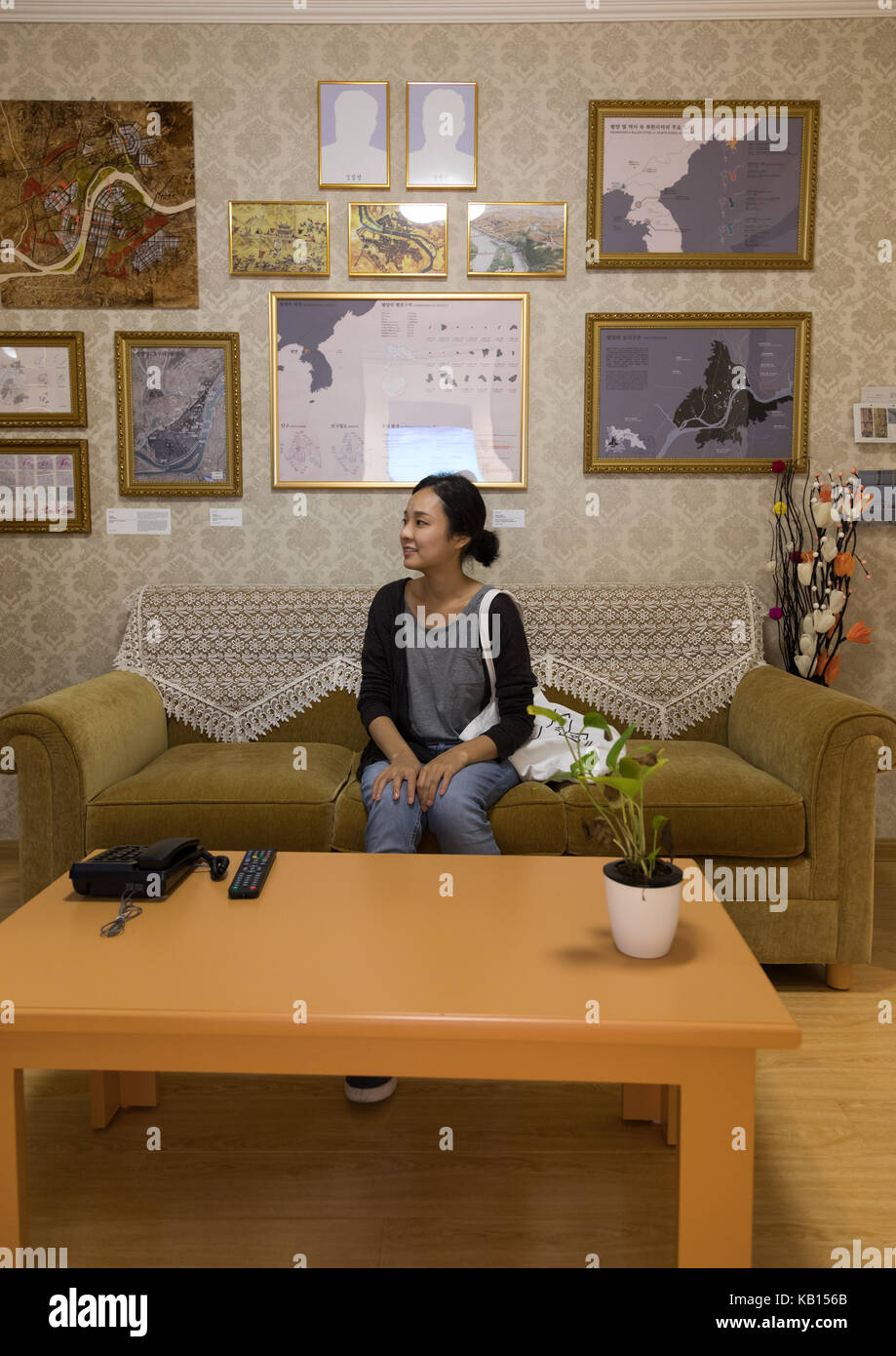 South korean visitor sit below the portraits of the dear leaders with the pictures removed during the exhibition pyongyang sallim showing a north korean apartment replica, National Capital Area, Seoul, South Korea Stock Photo