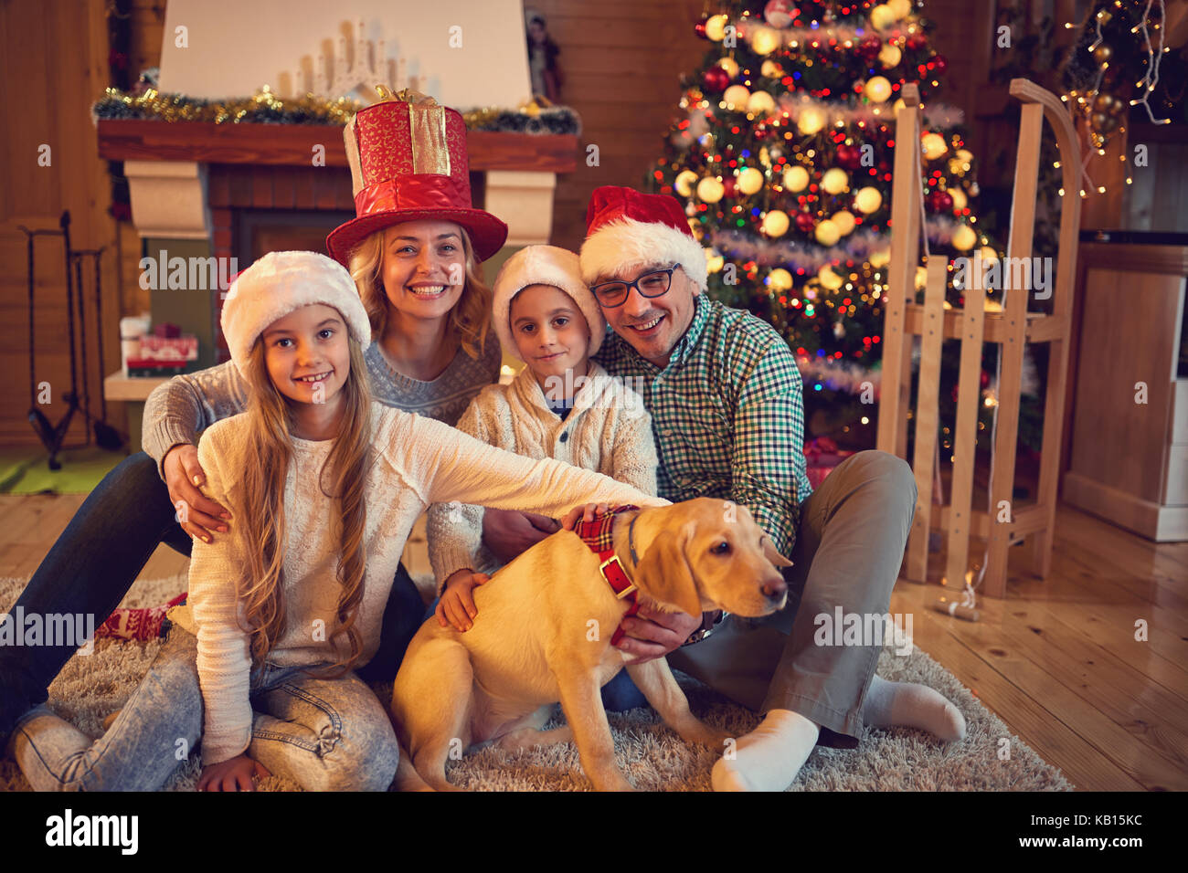 Smiling family and dog sitting by xmas tree Stock Photo