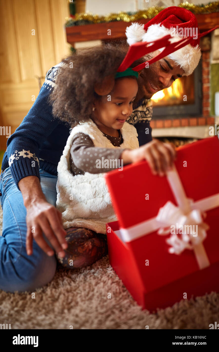 Little afro American girl open dadˈs Christmas present Stock Photo