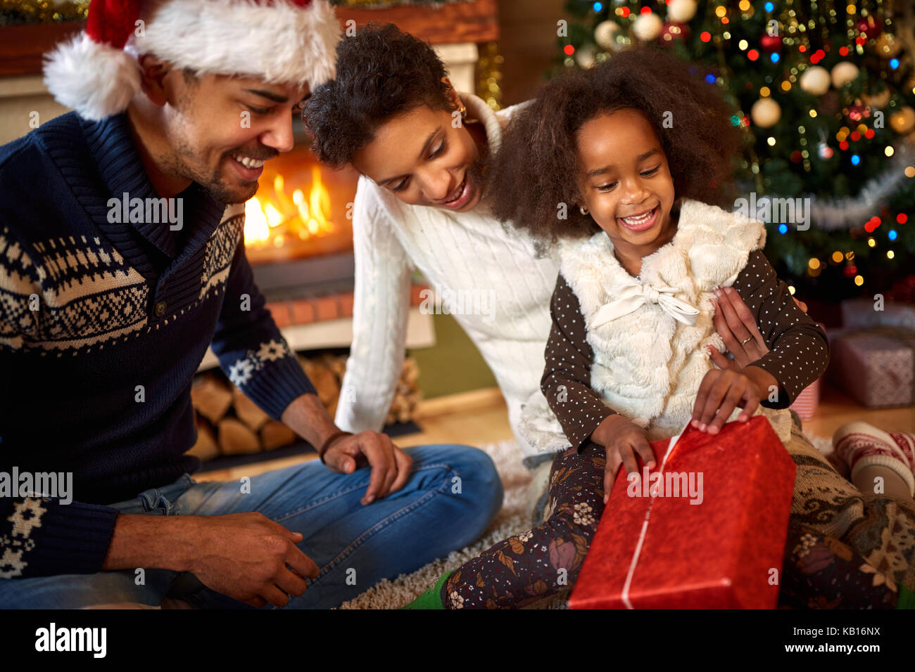 Little afro American little girl opening Christmas present with parents Stock Photo