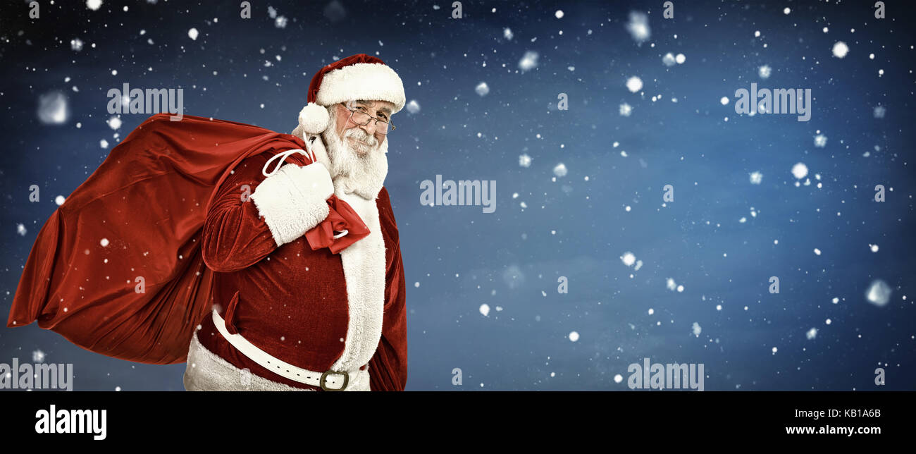 Santa Claus carrying a bag full of gifts, on copyspace background Stock ...