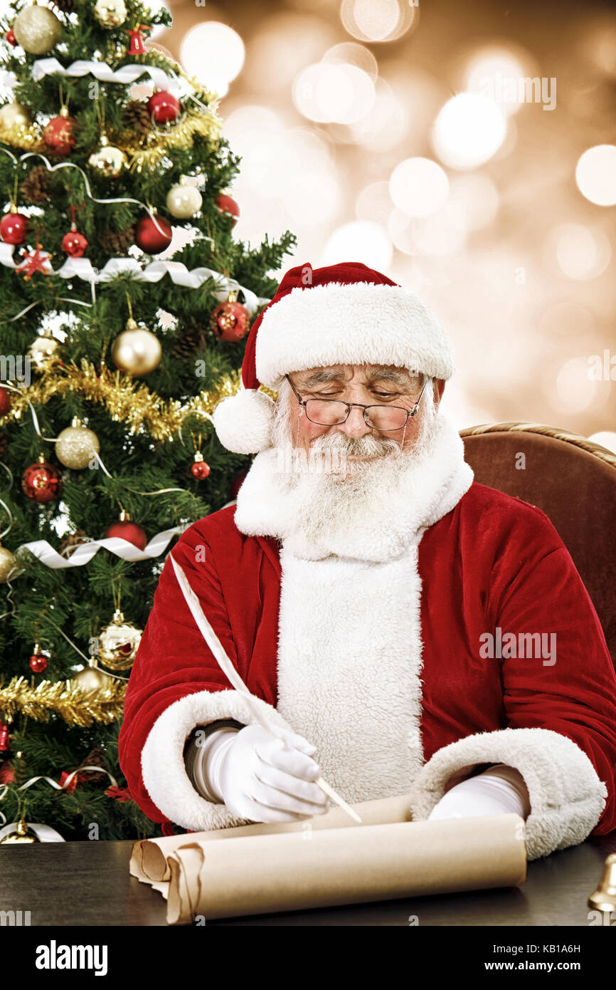 cheerful Santa Claus writing on scroll paper with quill Stock Photo