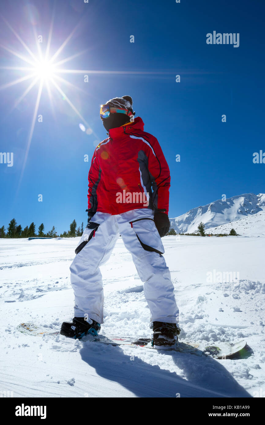 Snowboarder standing on board over sunny sky Stock Photo