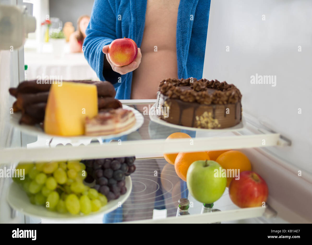 Fat man on diet take healthy apple from fridge instead of hard food Stock Photo