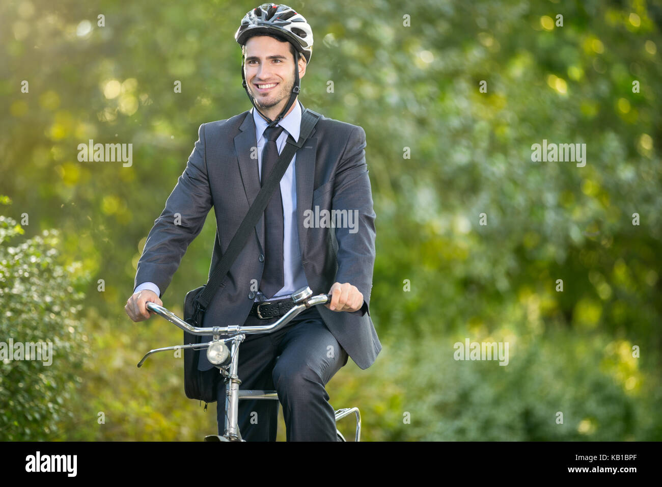 Positive young man in suit and bicycle helmet riding a bicycle to work Stock Photo Alamy