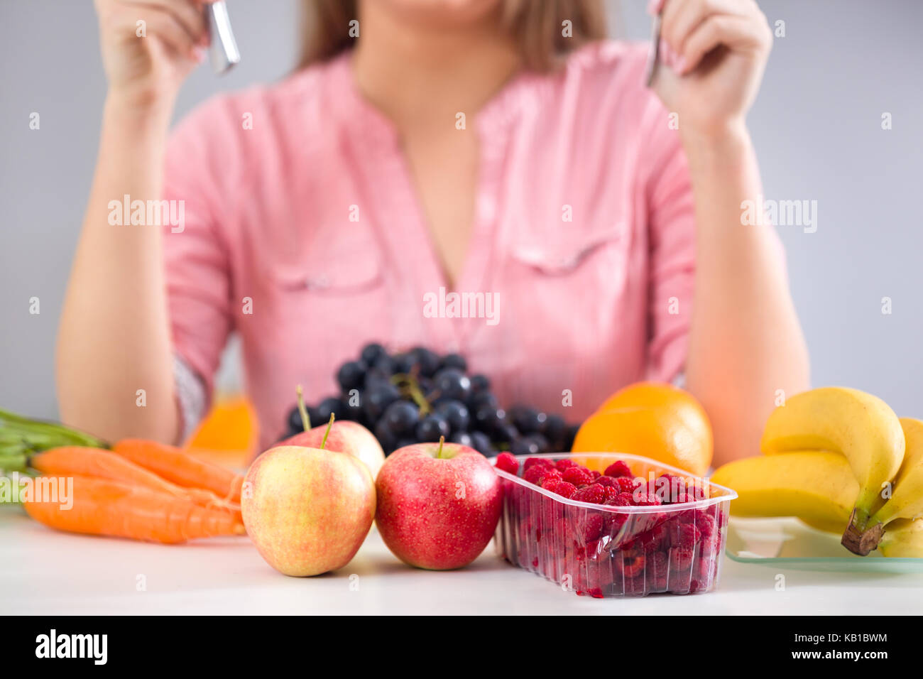 Female sitting at desk front lot of fruits, healthy food Stock Photo