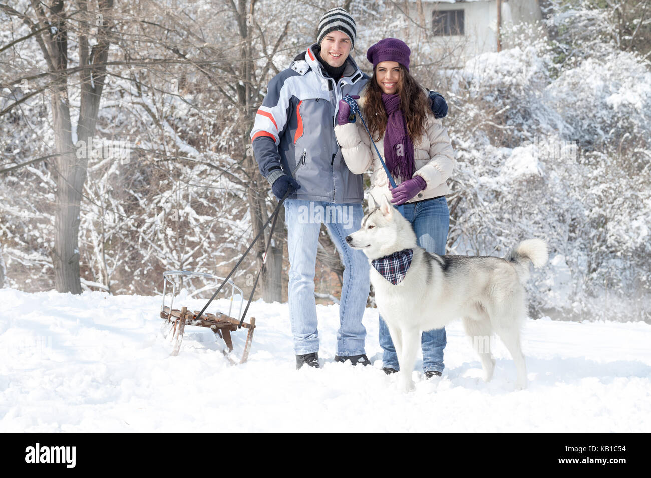 Happy young couple walking with dog snowy forest Stock Photo - Alamy