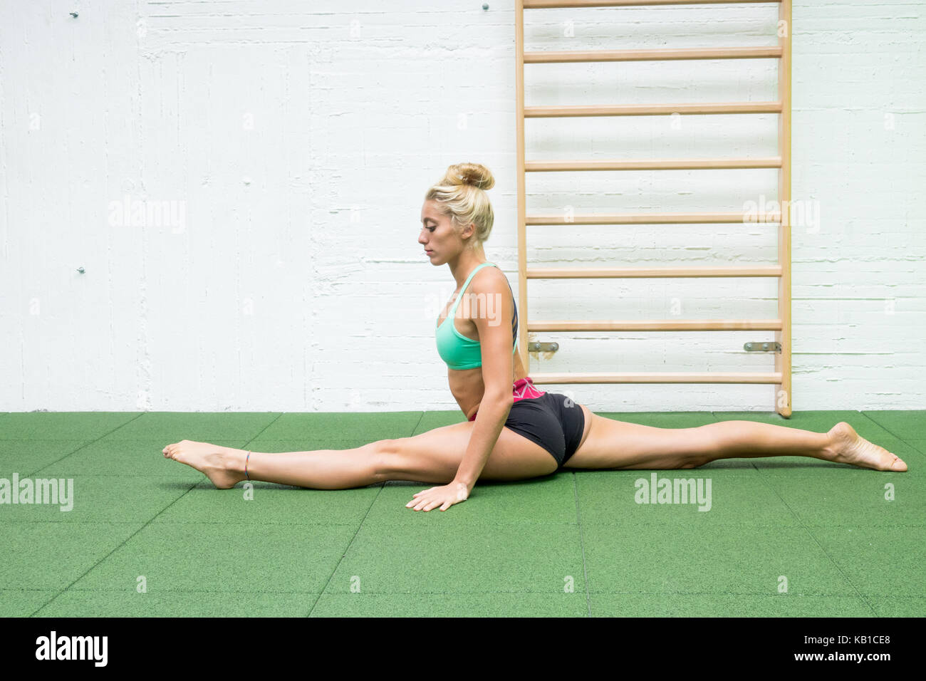 Fitness girl stretching legs doing pilates leg stretches exercises in gym.  athlete exercising abductor hip flexor muscle Stock Photo - Alamy