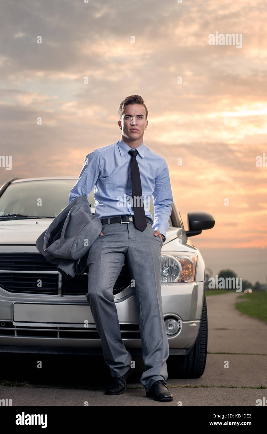 Handsome young man leaning on his car. Attractive gorgeous guy standing, outdoors - outside Stock Photo