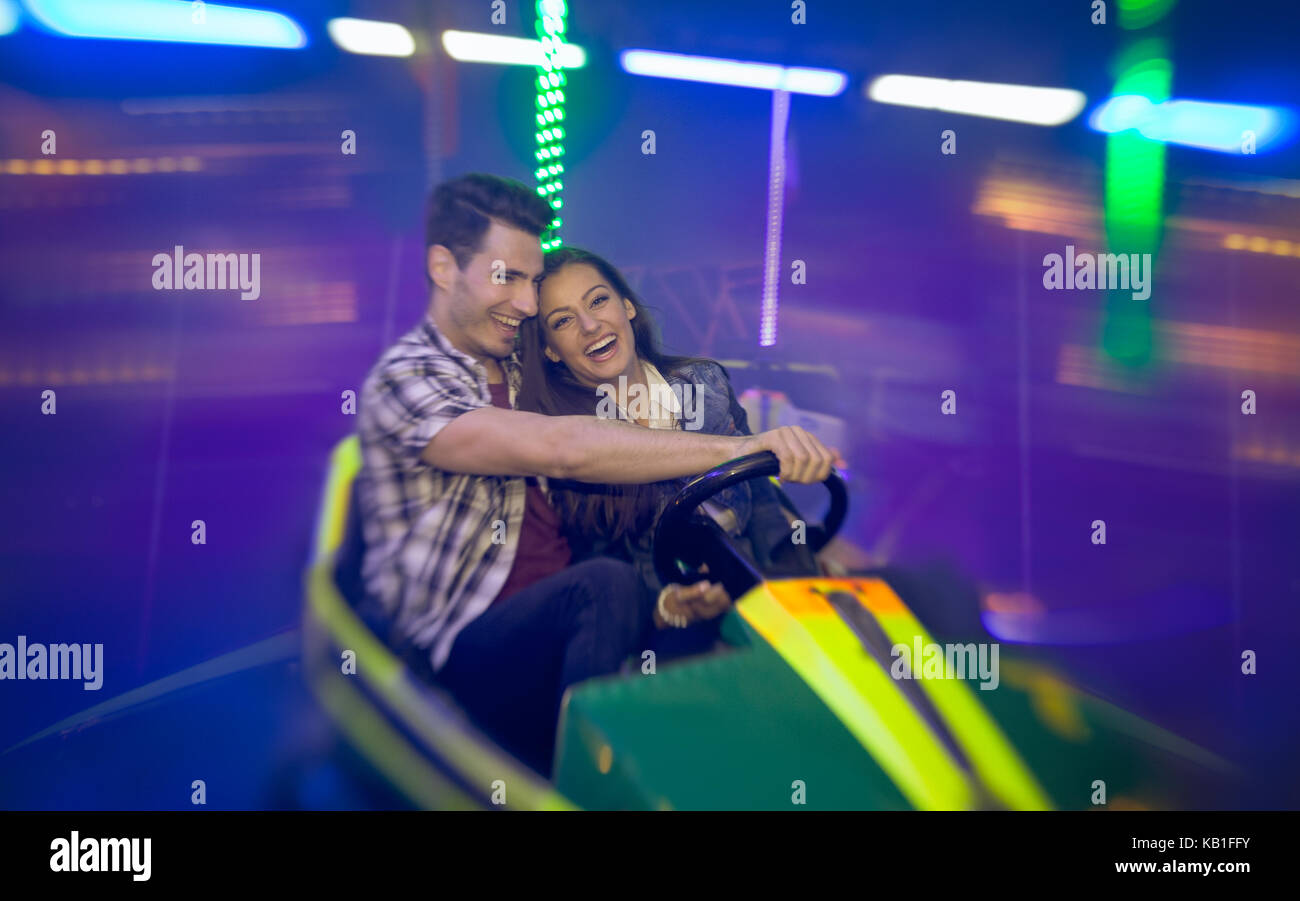 Happy couple having fun laughing and ride bumper car- shoot with lens ...