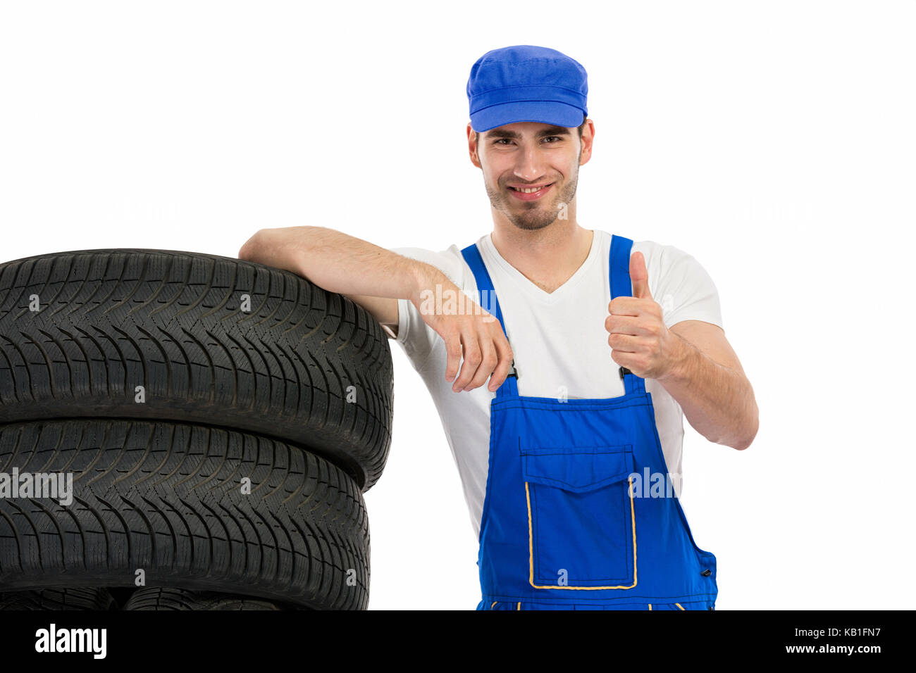 Young mechanic with tyre showing ok sign hand Stock Photo