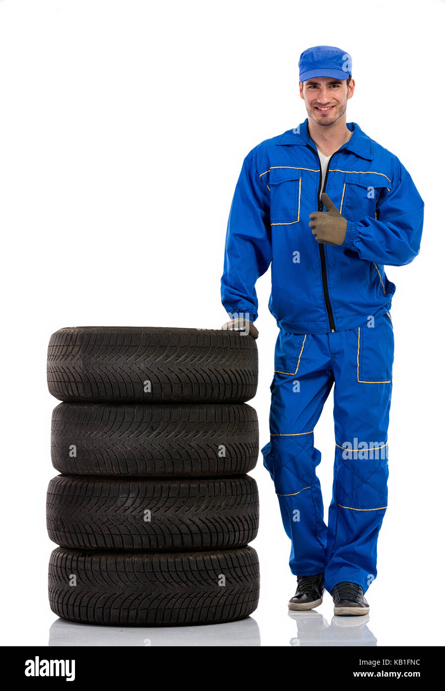 young car mechanic with pile car tires showing thumbs up Stock Photo