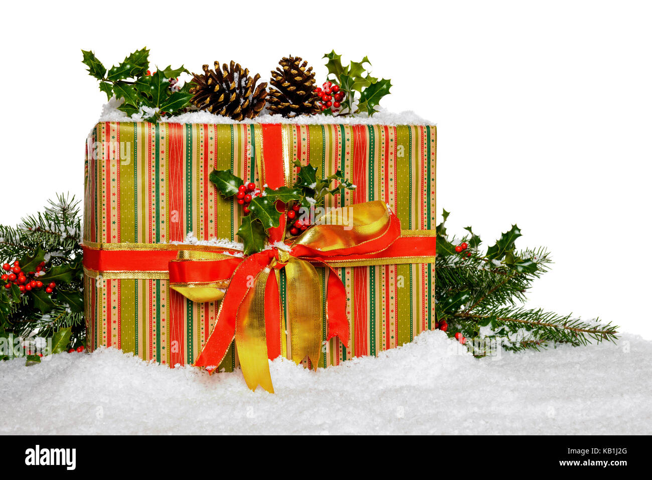 A gift wrapped Christmas present with holly and snow against a white background. Stock Photo