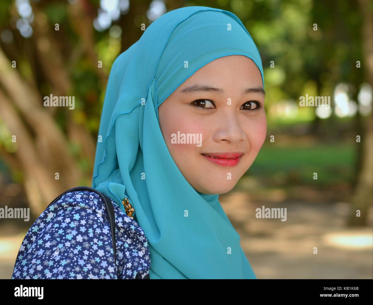 Beautiful, young Muslim woman from Malaysia, wearing a stylish turquoise hijab, throwing the famous Malay smile Stock Photo