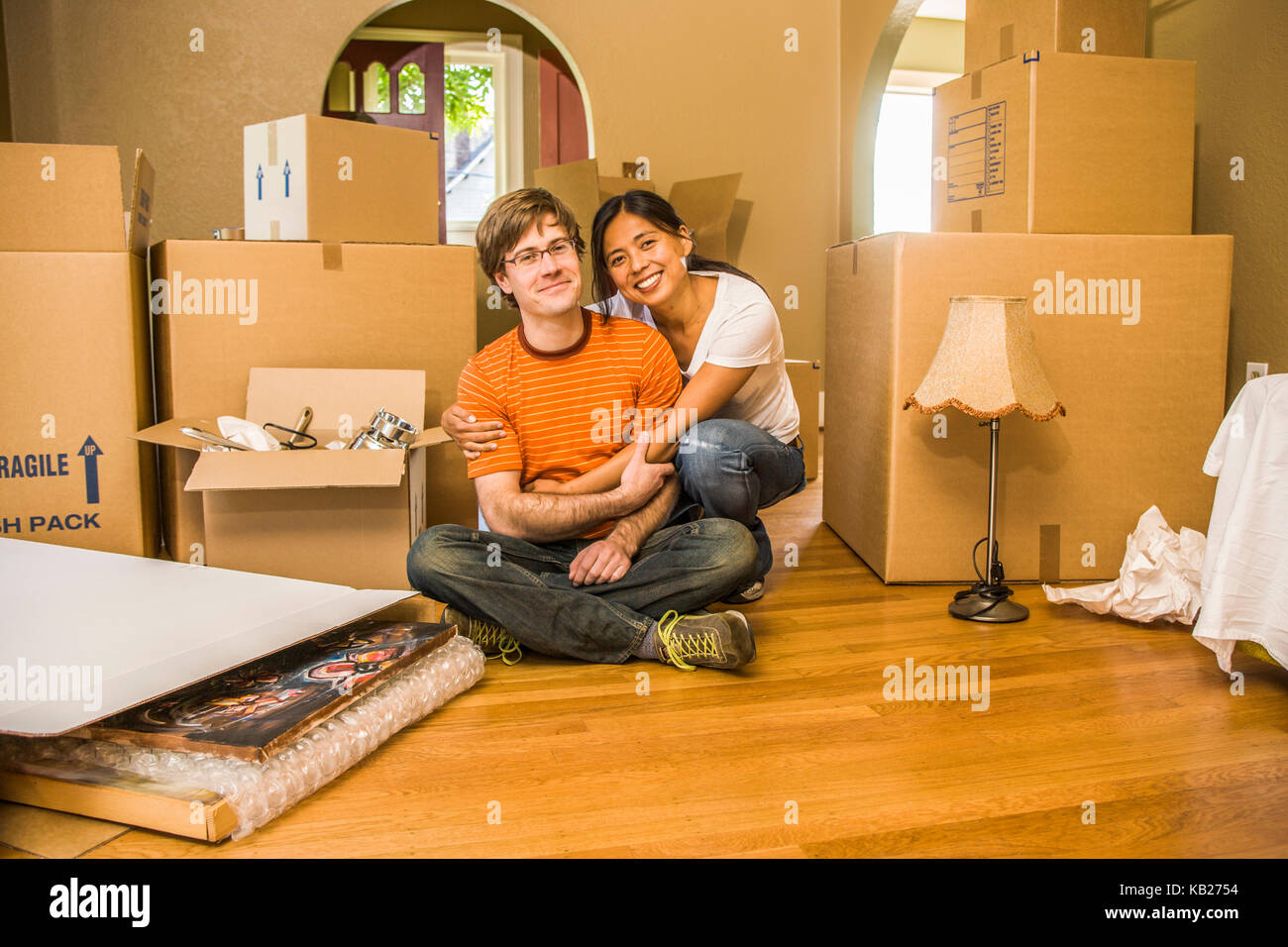 Portrait of a happy young couple in their new home surrounded by their ...